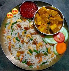 a silver plate topped with rice and veggies next to two bowls of sauce