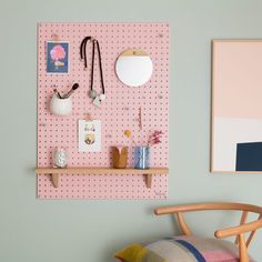 a pink pegboard mounted to the side of a wall next to a wooden chair