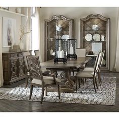 a dining room table with chairs around it and mirrors on the wall behind it in front of a window