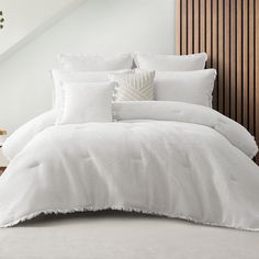 a bed with white sheets and pillows in a room