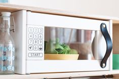 a white microwave oven sitting on top of a wooden shelf next to a green plant