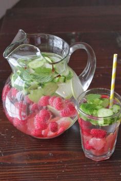 a pitcher and glass filled with watermelon, cucumber and raspberries