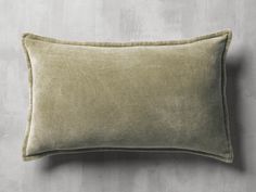 an olive green velvet pillow on a grey wall