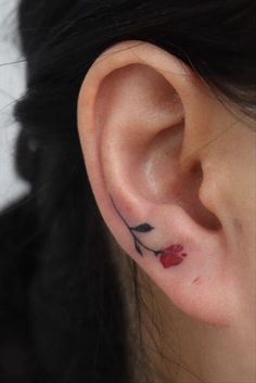 a close up of a person's ear with a small flower tattoo on it