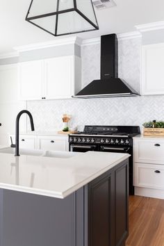 a kitchen with an island, stove and range hood in the middle of the room