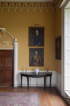 a room with two paintings on the wall and a small table in front of it