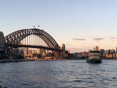 a boat is in the water near a large bridge and some buildings on the other side