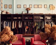 two red chairs sitting in front of a closet filled with clothes