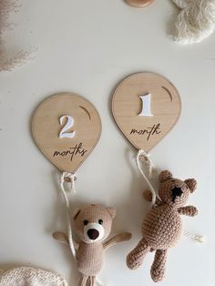 two teddy bears are hanging on the wall next to each other with wooden signs that say 1, 2, and month