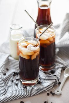 two glasses filled with iced coffee and ice cream on top of a table next to some spoons