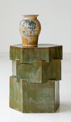 a vase sitting on top of three stacked blocks