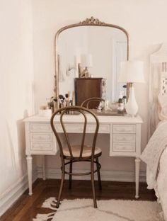 a bedroom with a chair, desk and mirror