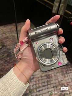 a person holding a camera in their hand with beads on the wrist and bracelet attached to it