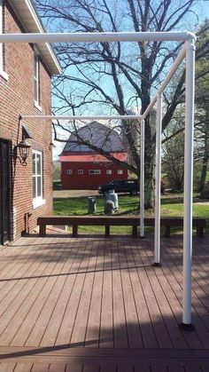 a wooden deck with a white pergolan on it and a red barn in the background