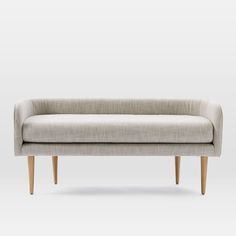 an upholstered couch with wooden legs and a light colored fabric on the back