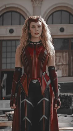 a woman in a red and black cosplay standing on the street with her hands behind her back