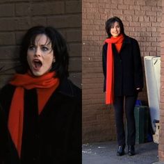 a woman standing in front of a brick wall wearing an orange scarf and black coat