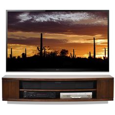 a flat screen tv mounted to the side of a wooden entertainment center in front of a sunset