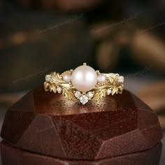 a pearl and diamond ring sitting on top of a wooden box