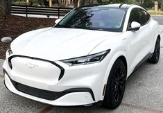 a white car is parked on the side of the road in front of some trees