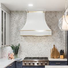 a kitchen with blue cabinets and white counter tops, gold trimming on the hood