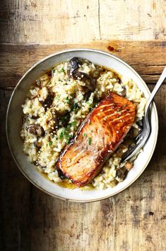 salmon and mushroom riso with rice in a white bowl on a wooden table top