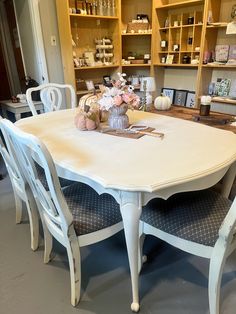 a white table and chairs in a room with shelves full of items on the wall