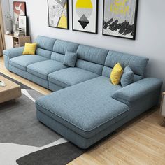 a living room with blue couches and yellow pillows on the floor, two framed pictures above them