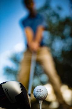 a close up of a golf ball on the tee with a person in the background