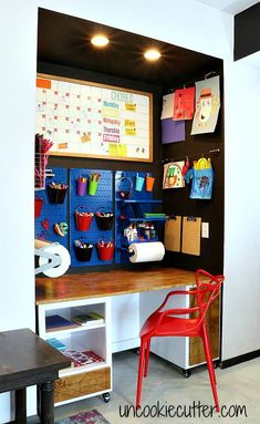 a room with a desk, chair and storage bins on the wall next to it