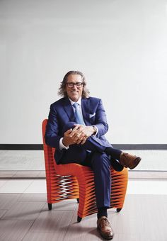 a man in a suit and tie sitting on an orange chair