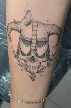 a woman's leg with a skull and horns tattoo on it