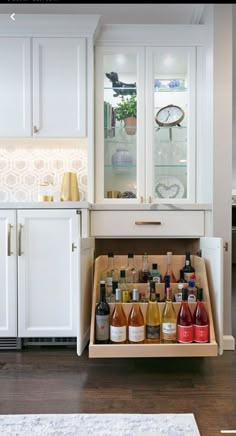 an open cabinet in a kitchen filled with bottles