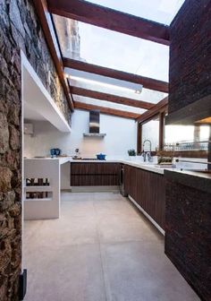 an open kitchen with stone walls and flooring on the outside, along with skylights