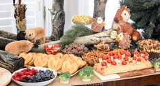 an assortment of fruits and pastries on a table with stuffed animals in the background