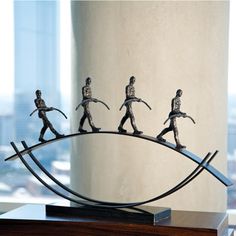 four figurines are walking on a wire in front of a window