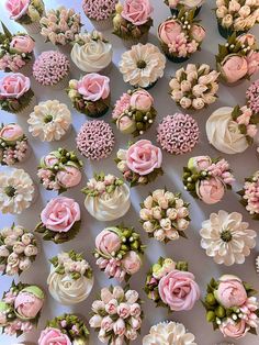 cupcakes decorated with pink and white flowers are arranged in rows on a table