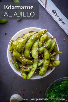 edamame al ajillo in a white bowl with sesame seeds on the side