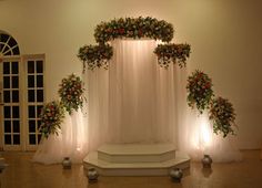 a white stage decorated with flowers and candles