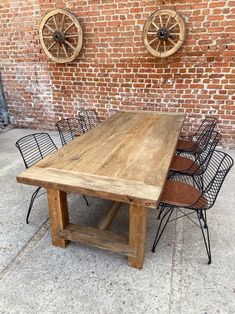 a wooden table and chairs in front of a brick wall with two wheel wheels on it