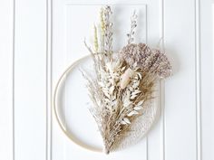 a wreath with dried flowers hanging on the front door, next to a wall decoration