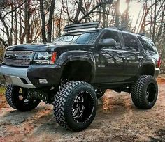 a large black truck parked on top of a dirt road