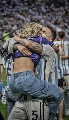 two people hugging each other in front of a crowd at a soccer game with fans