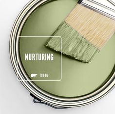 a green paint can with a brush in it and the words nurturing above it