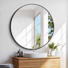 a round mirror hanging on the wall above a sink in a room with white walls