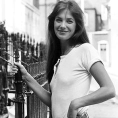 a woman standing next to a fence smiling