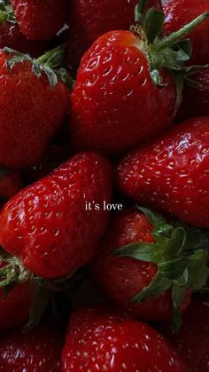 a pile of red strawberries with the words it's love