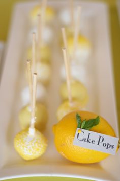 there are some lemons and cake pops on the plate with sticks sticking out of them