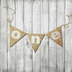 a gold and white banner with the word one hanging from it's side on a wooden