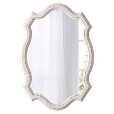 a white mirror sitting on top of a table next to a vase filled with flowers